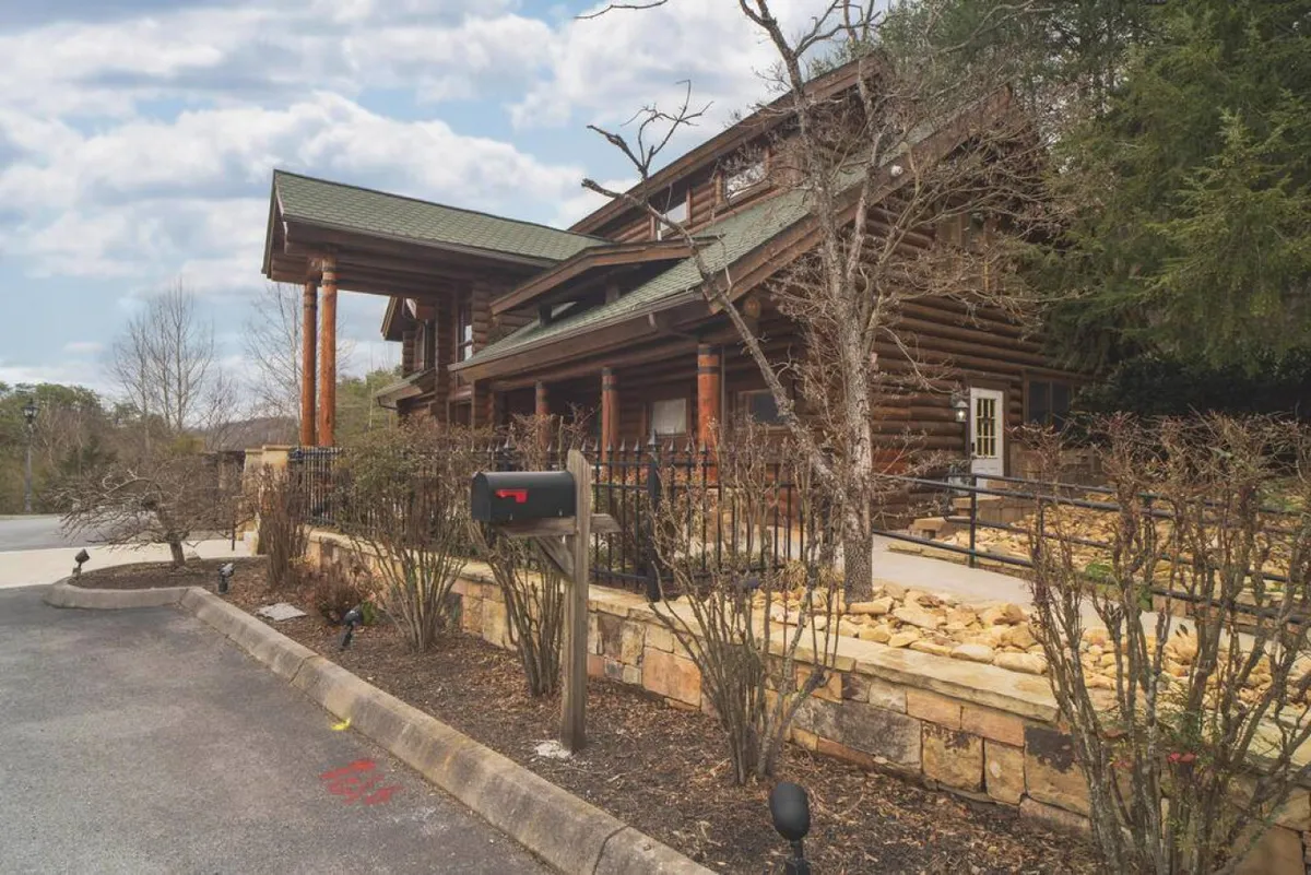 A welcoming grilling area outside a log cabin structure, complete with a manicured stone wall and a family-friendly, open-air setting. The area is ideal for barbecues and social gatherings, embodying the spirit of classic resort cookouts.