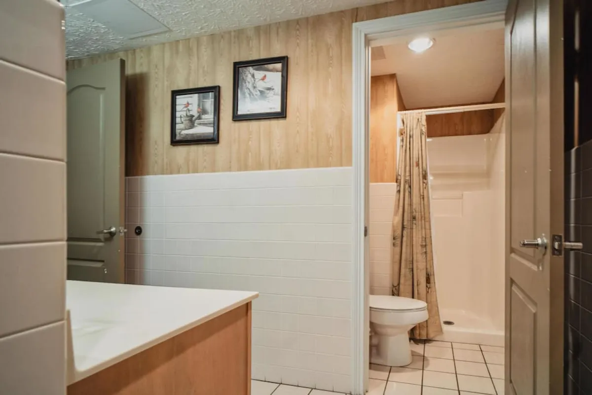 This image presents a clean and modern bathroom with a sink, toilet, and a shower area accented by framed pictures. The space is calm and welcoming, ideal for personal grooming and refreshment.