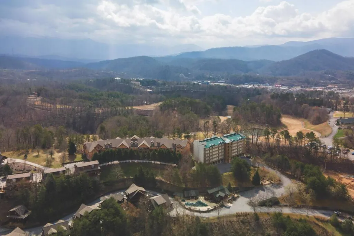 This image captures a sweeping view of the mountain range with resort buildings nestled among lush greenery and winding roads. The scene offers a sense of the natural beauty, tranquility, and adventure available just outside the condo, emphasizing the proximity to the Great Smoky Mountains and the inviting atmosphere of the resort area.