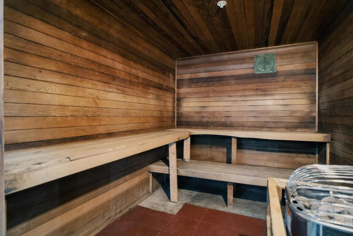 A cozy sauna space featuring classic wooden benches and paneling, with a visible heating element. The room exudes a sense of warmth and relaxation, perfect for unwinding after a round of golf or an adventurous day exploring the area.