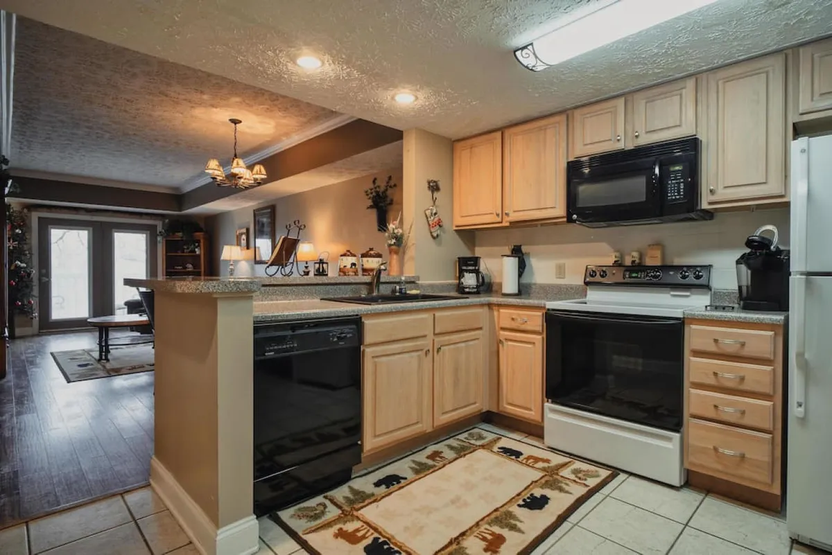 This image showcases a kitchen with a granite countertop, black appliances, and wooden cabinets. There are decorative items on the countertop, adding a cozy, lived-in feel. The scene highlights a functional and inviting kitchen space ideal for cooking and gathering.