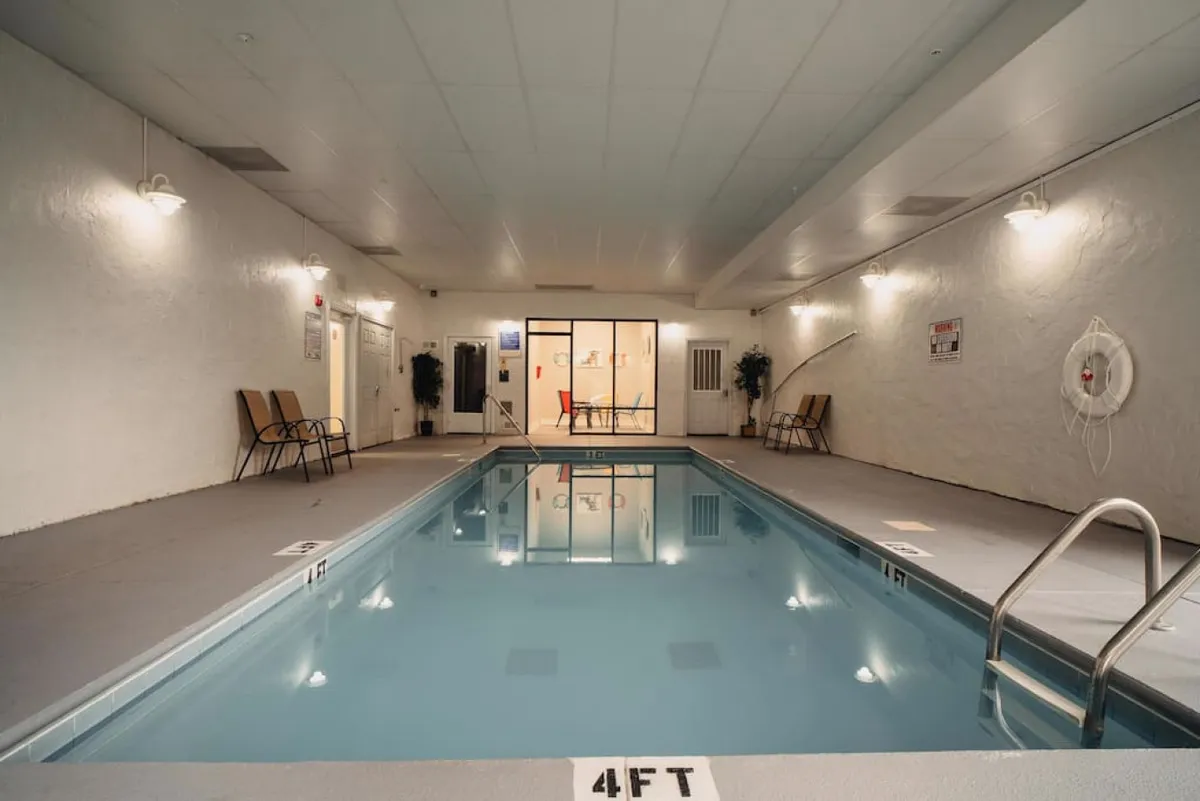 A tranquil indoor pool area with lounge chairs, potted plants, and soft evening lighting. The setting is calm and inviting, perfect for unwinding after a day of exploring or enjoying a spa-like experience as a couple.