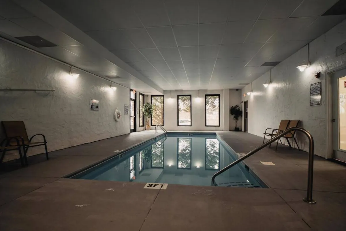 An inviting indoor pool area with large windows letting in natural light and offering views outside. The poolside seating provides a comfortable space to unwind, and the tranquil ambiance suggests a perfect spot for post-golf relaxation.