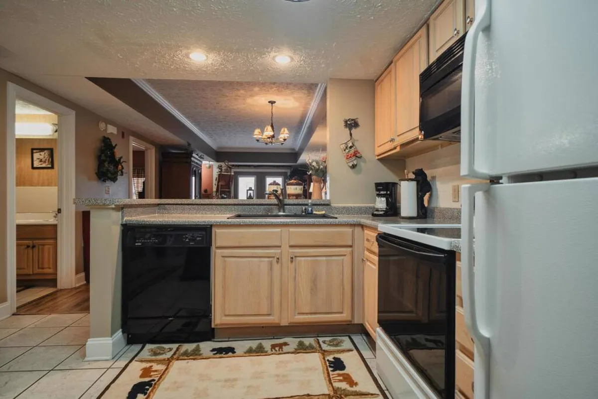 A warm, welcoming kitchen with modern appliances, wooden cabinetry, and a cozy rug featuring animal motifs. The space feels inviting for meal preparation and gathering, suggesting opportunities for guests to fuel up before their next adventure.